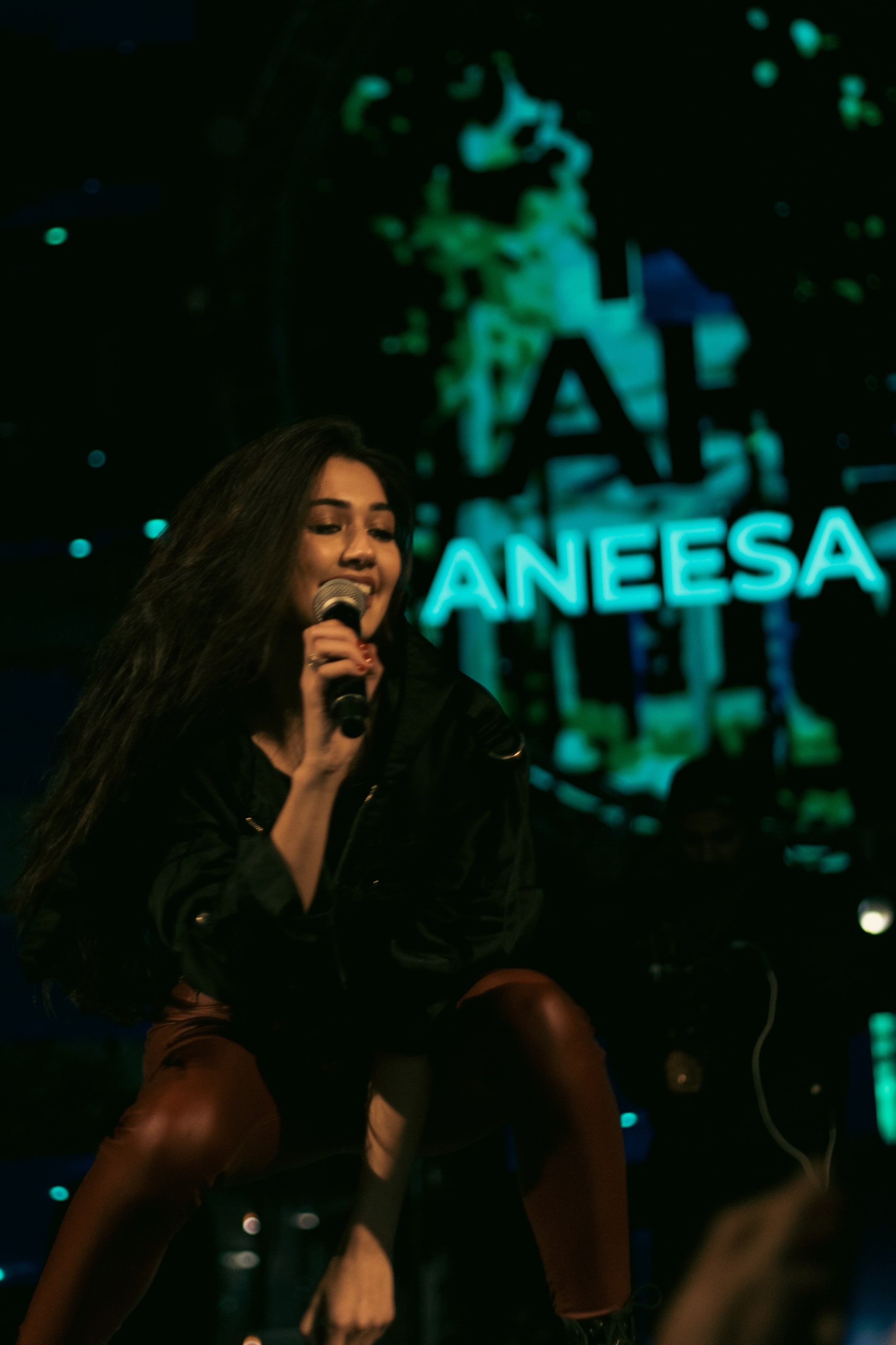 Aneesa performing live on stage, her name in lights